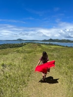 a woman in a red dress is walking through a field