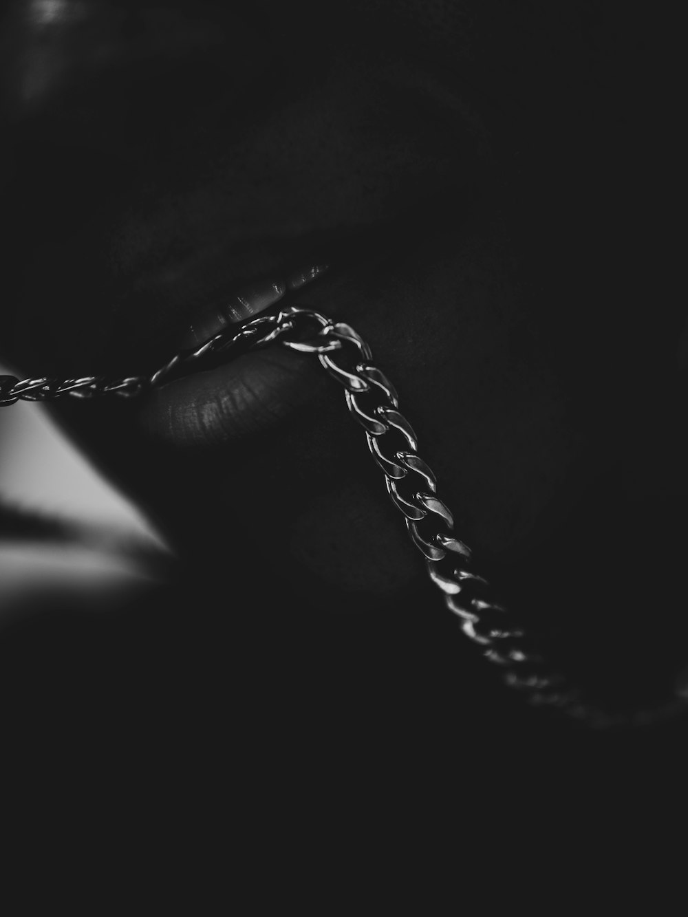 a black and white photo of a person's hand holding a chain