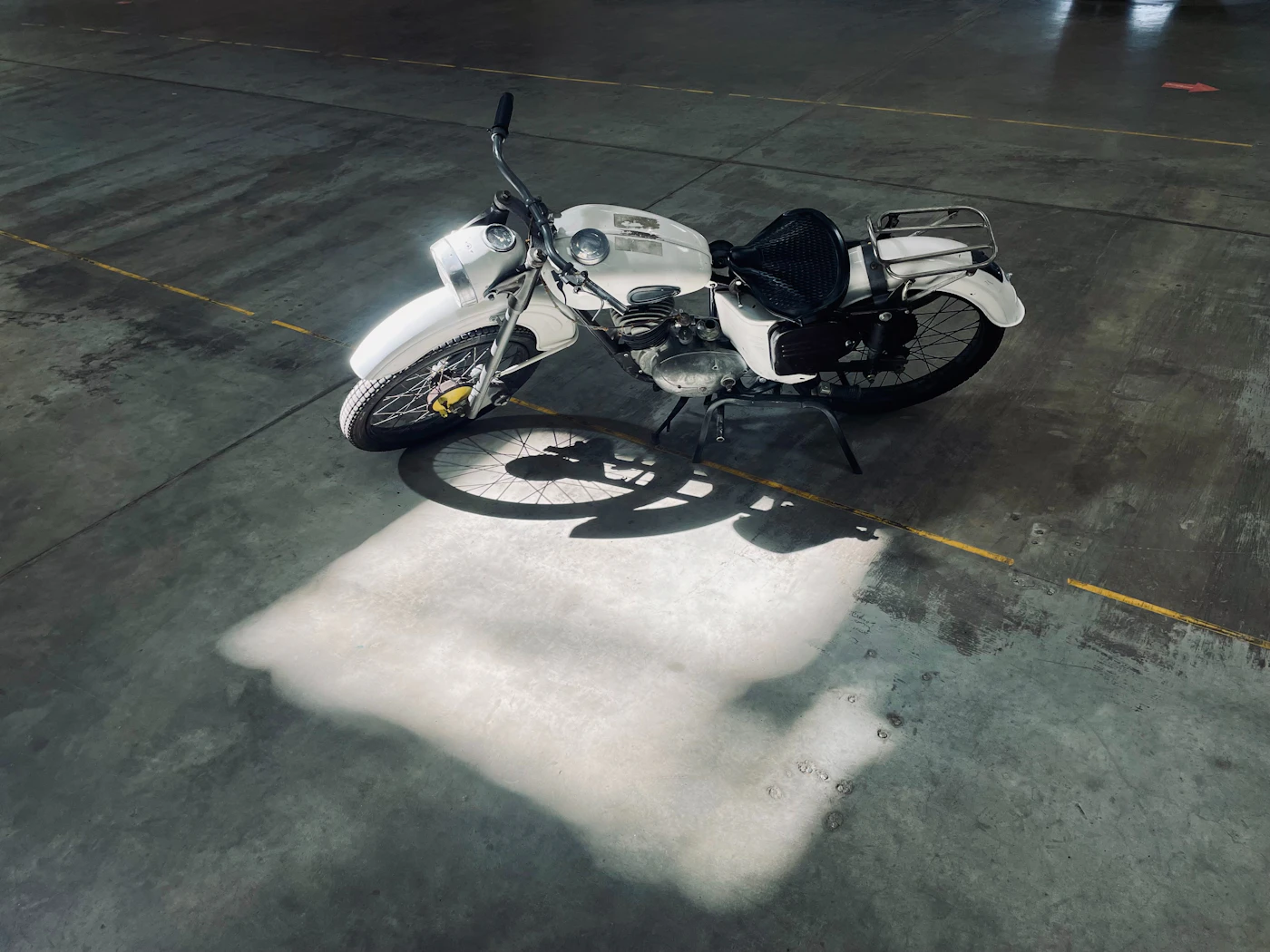 Bobber motorcycle lying in raking sunlight on concrete