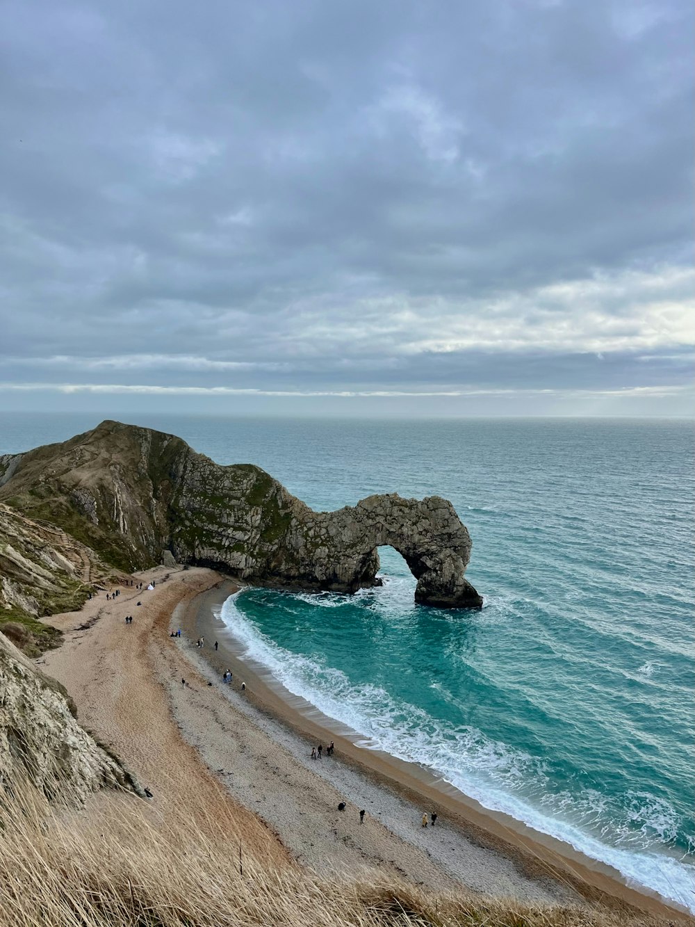 a beach with a large rock formation in the middle of it