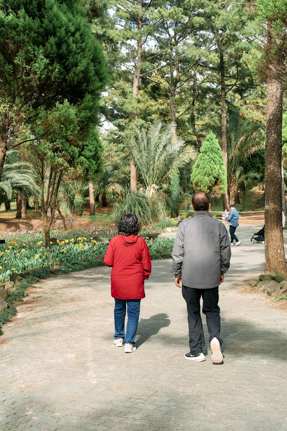 a man and a woman walking down a path in a park