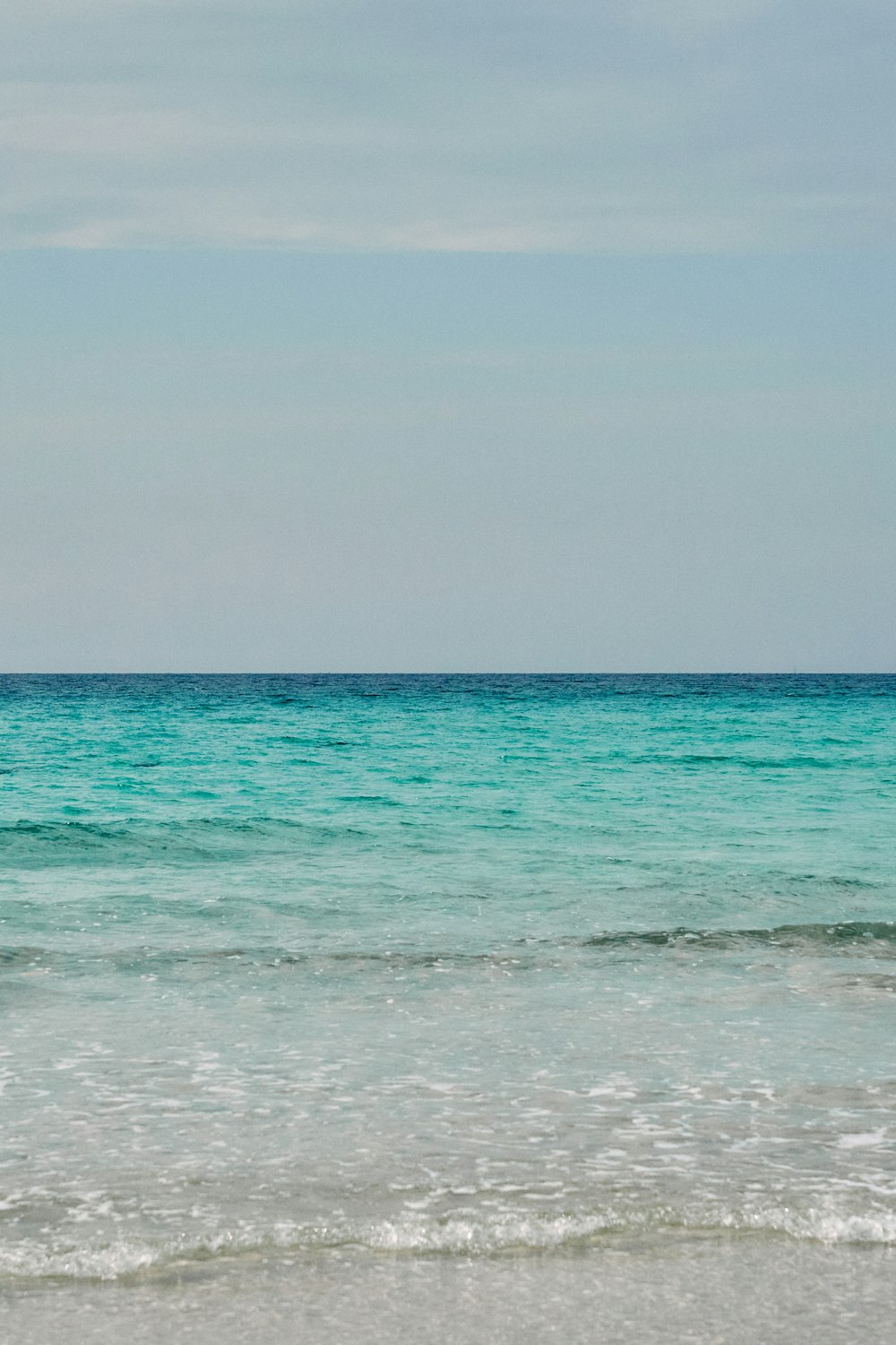 a person walking on the beach with a surfboard