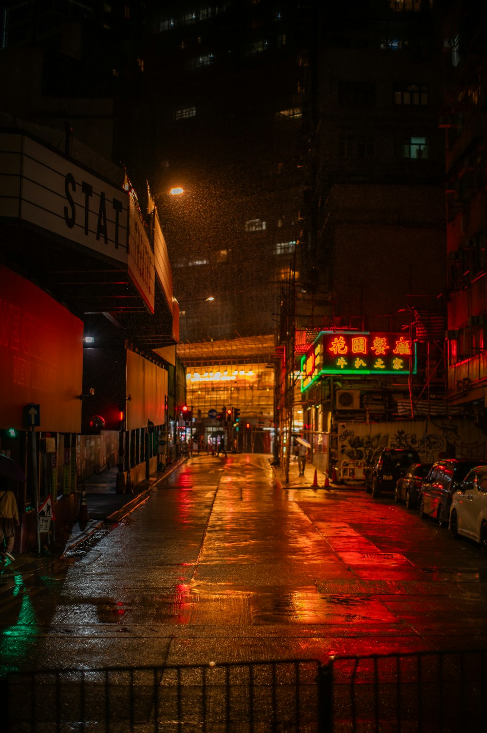 a city street at night with cars parked on the side of the road