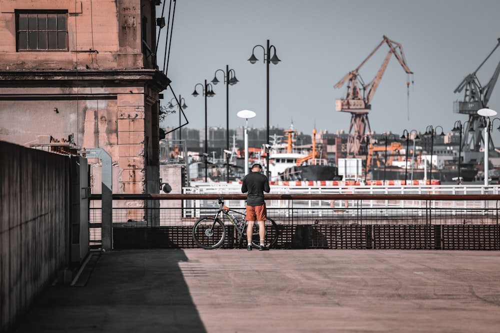 a man standing next to a bike on a sidewalk