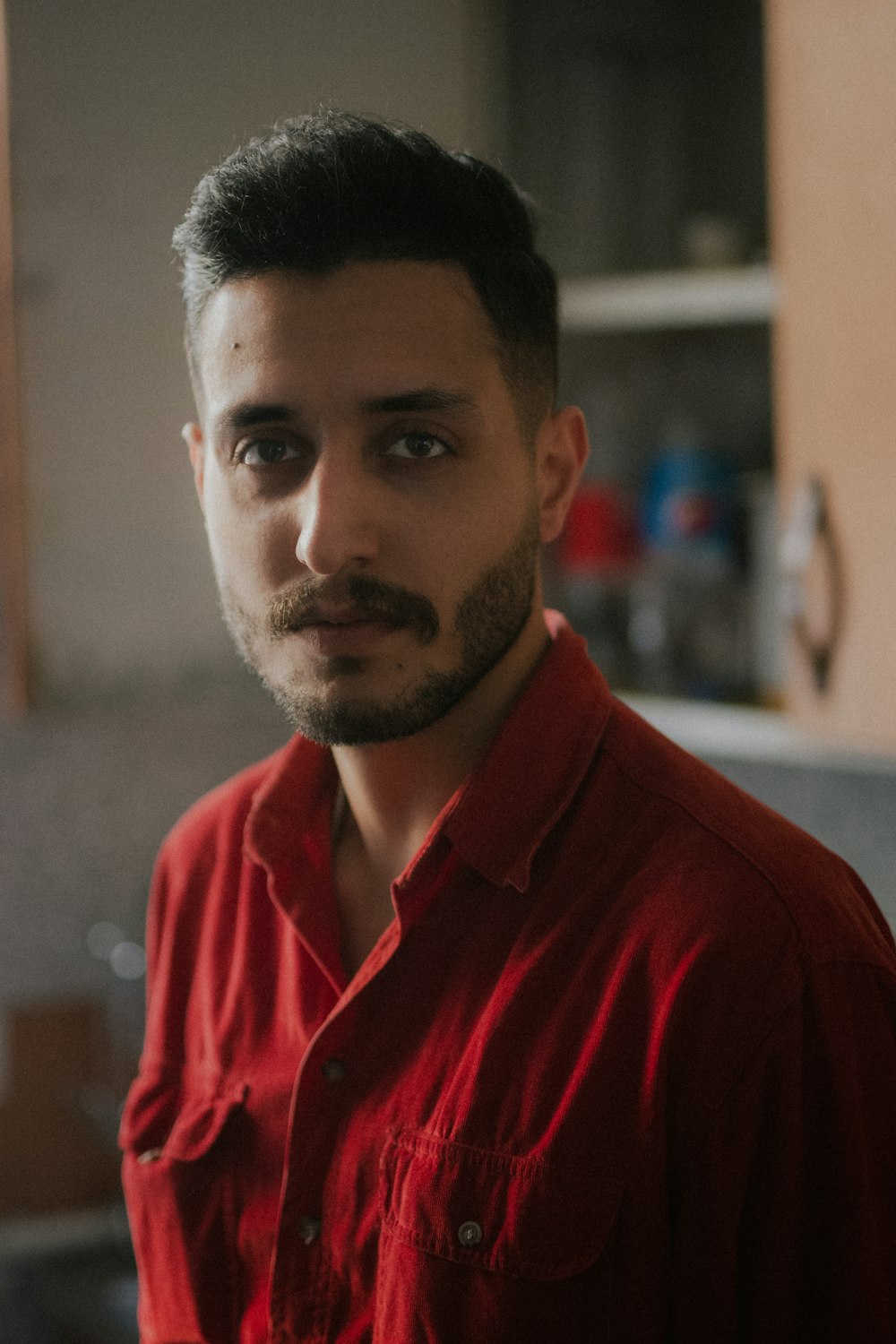 a man in a red shirt standing in a kitchen
