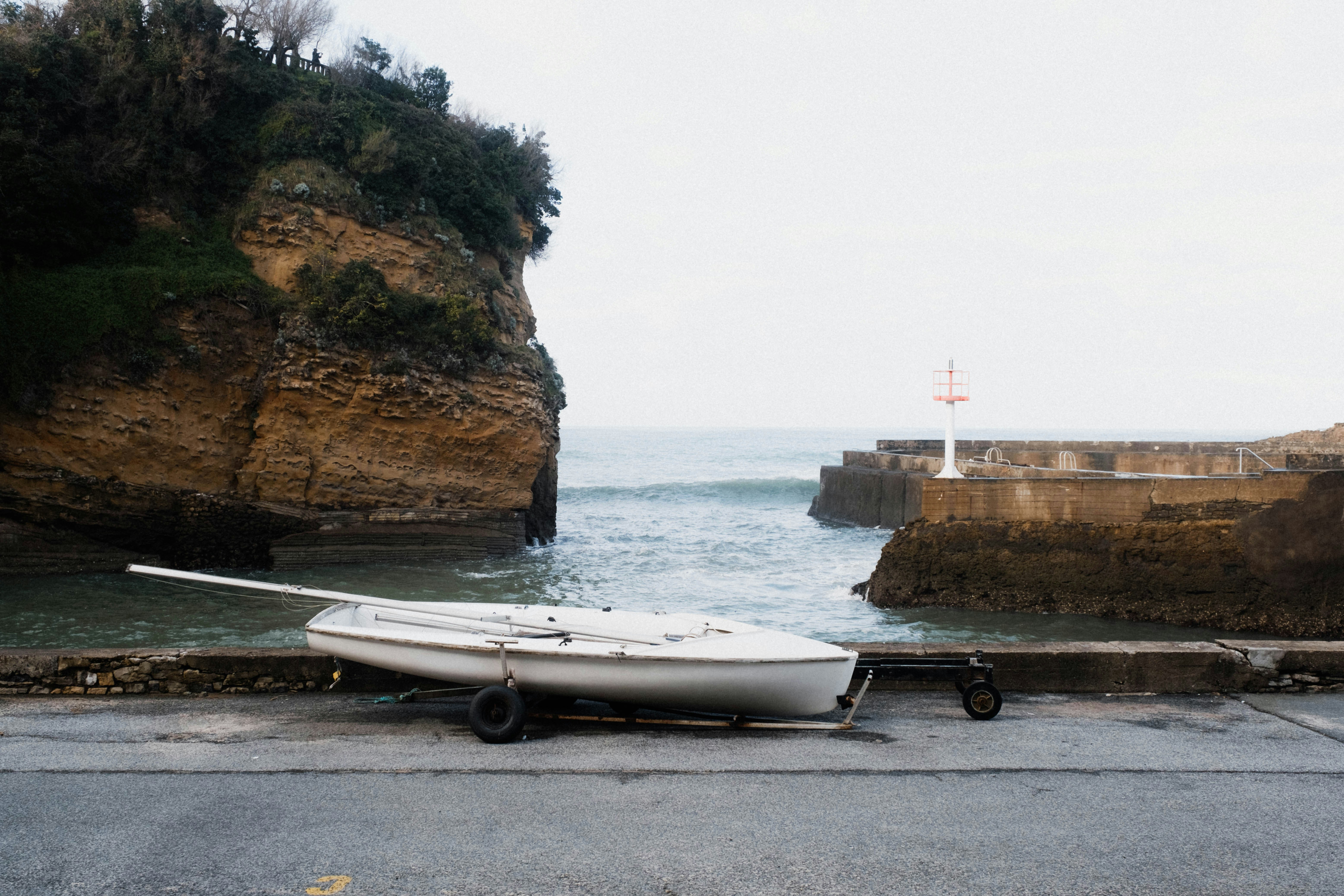 um barco branco sentado no topo de uma estrada ao lado do oceano