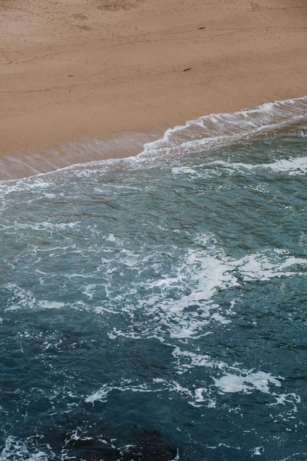 a man riding a surfboard on top of a wave covered beach