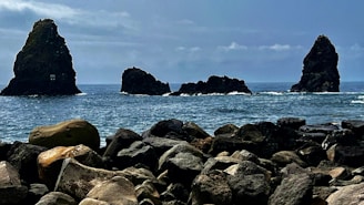 a rocky beach with rocks and a boat in the water