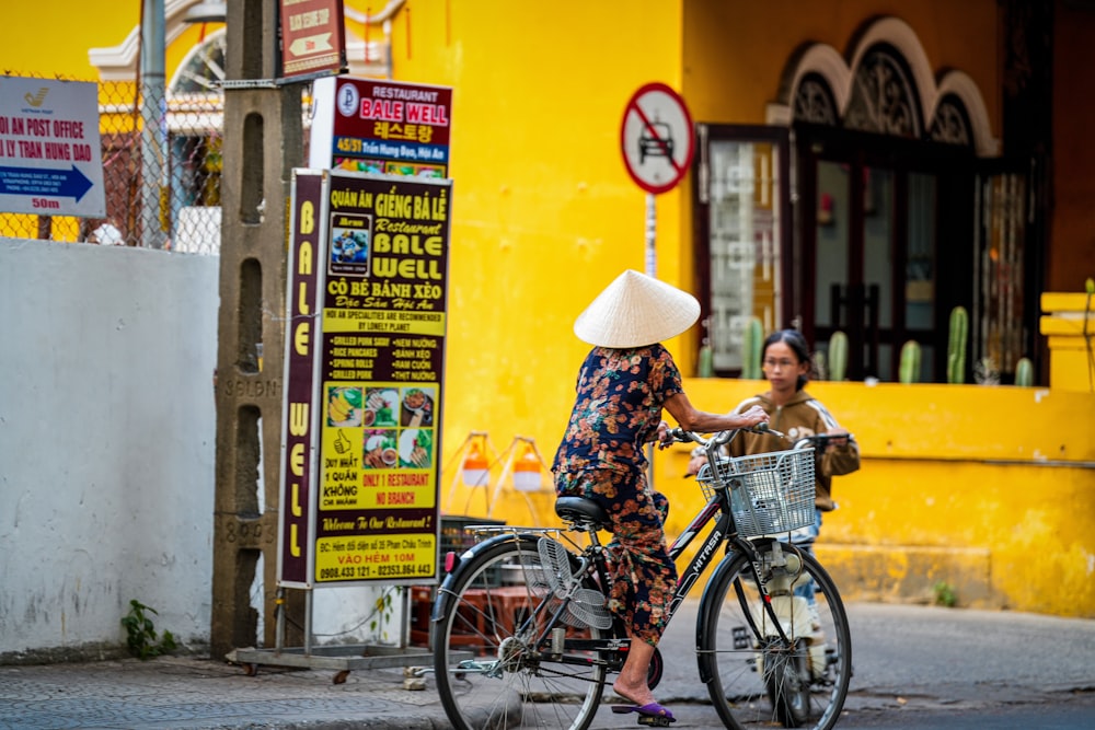 a woman riding a bike down a street next to a yellow building