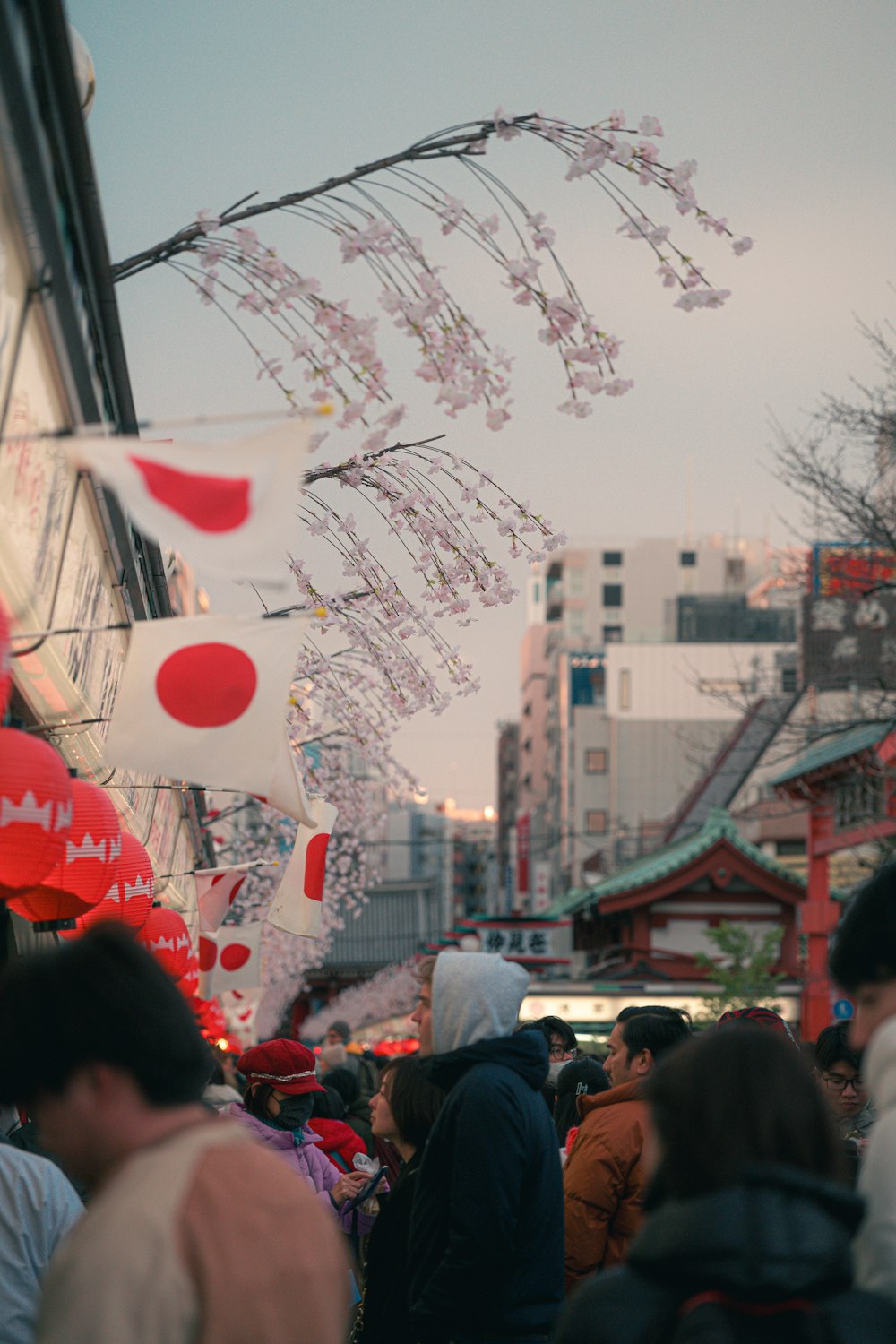 a crowd of people walking down a street next to tall buildings