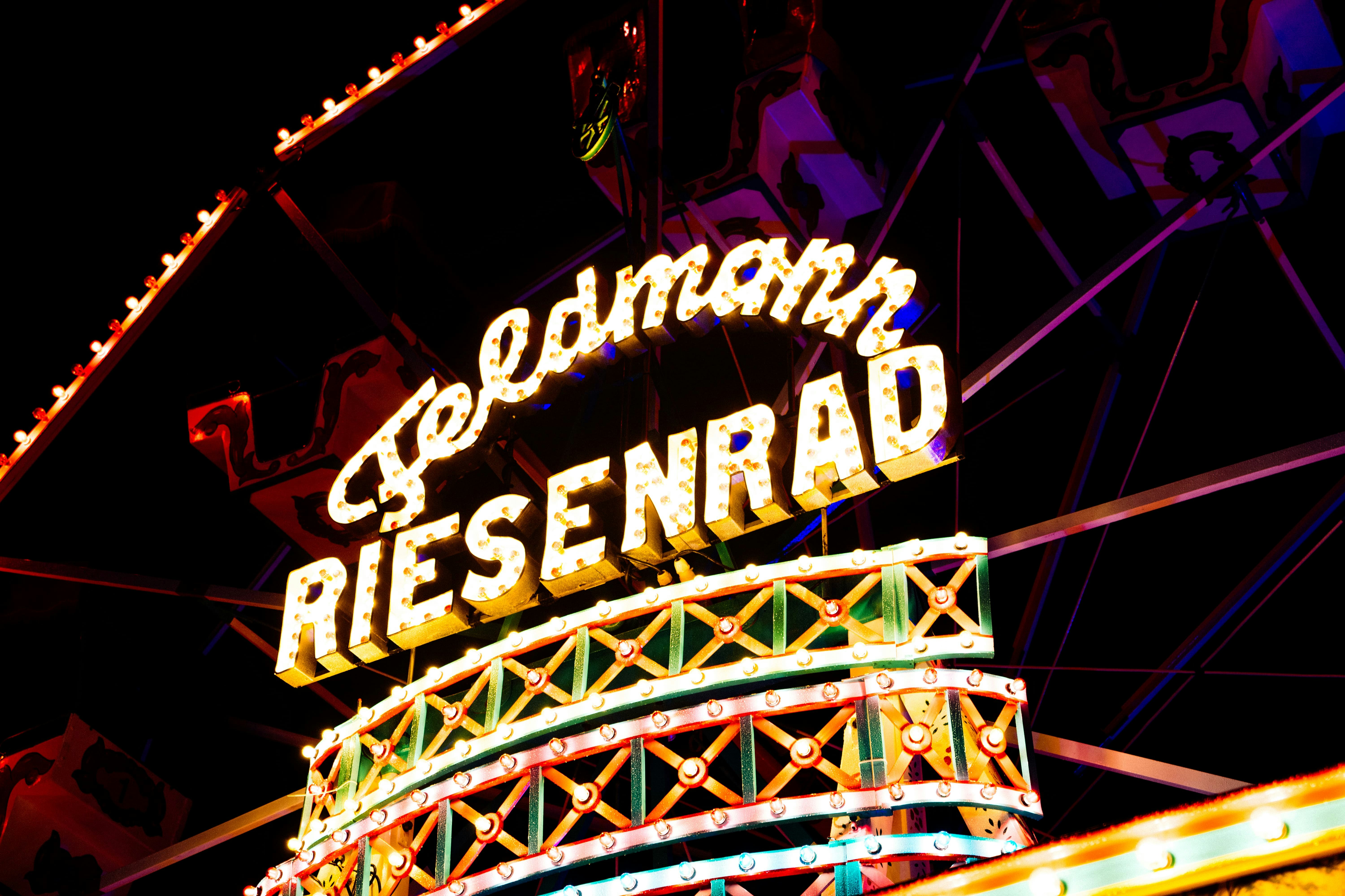 Illuminated Riesenrad Ferris wheel sign at a German funfair at night