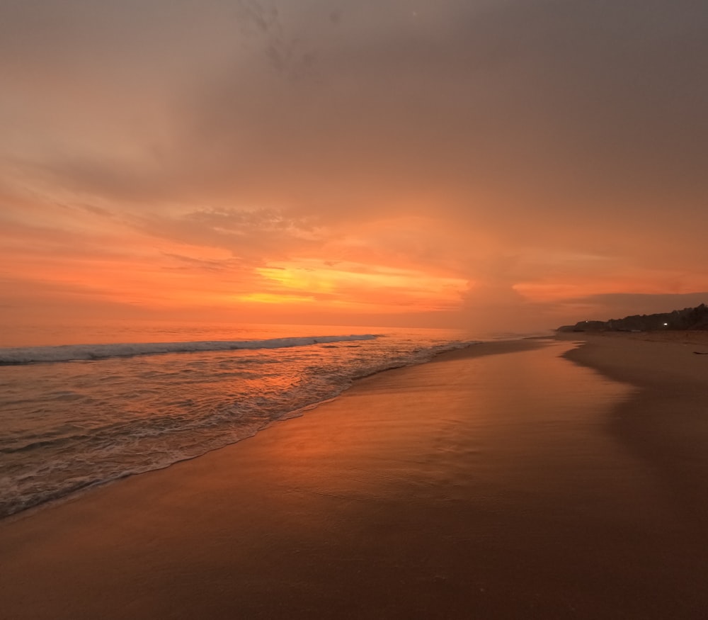 the sun is setting over the ocean on the beach