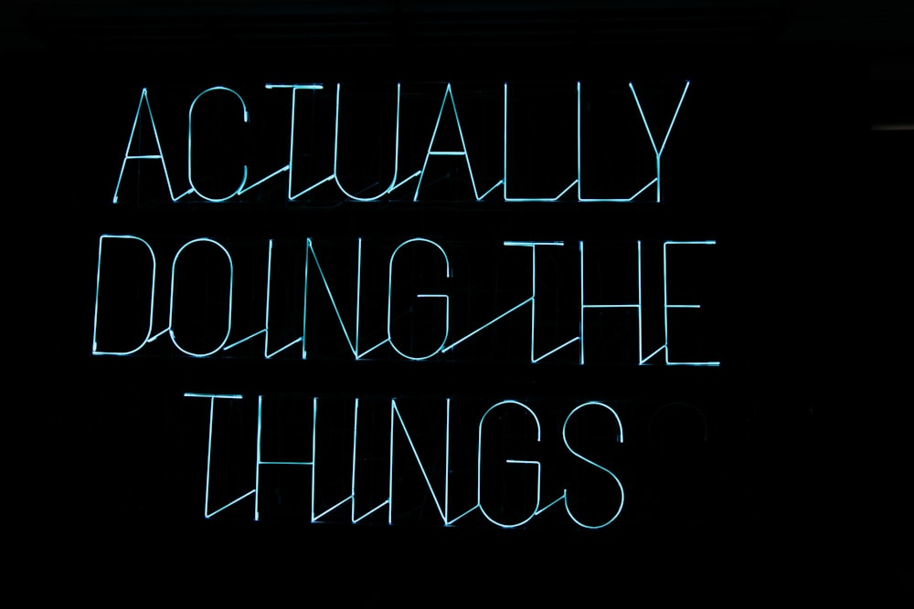 a neon sign that says actually doing the things