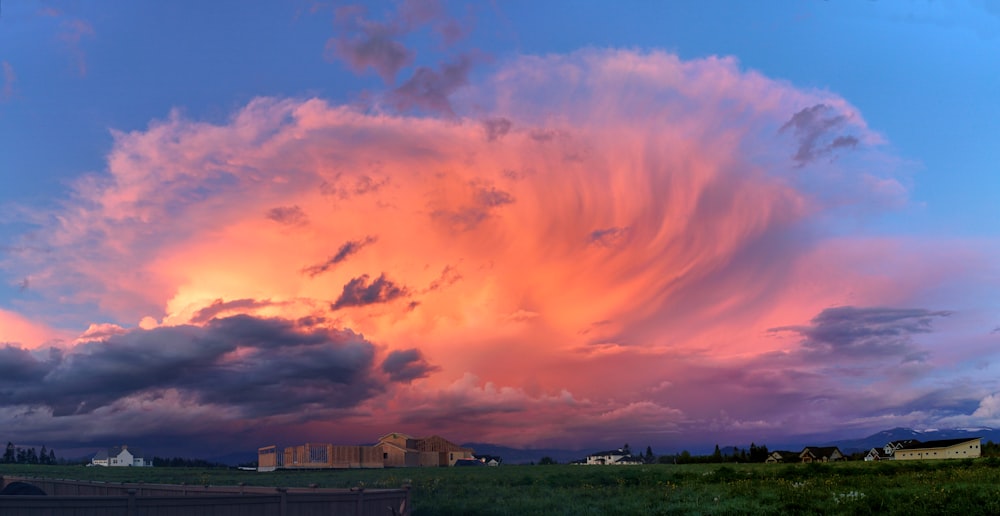 a large cloud is in the sky over a field