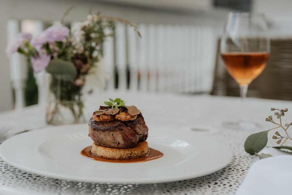 ein weißer Teller mit einem Stück Fleisch in Soße