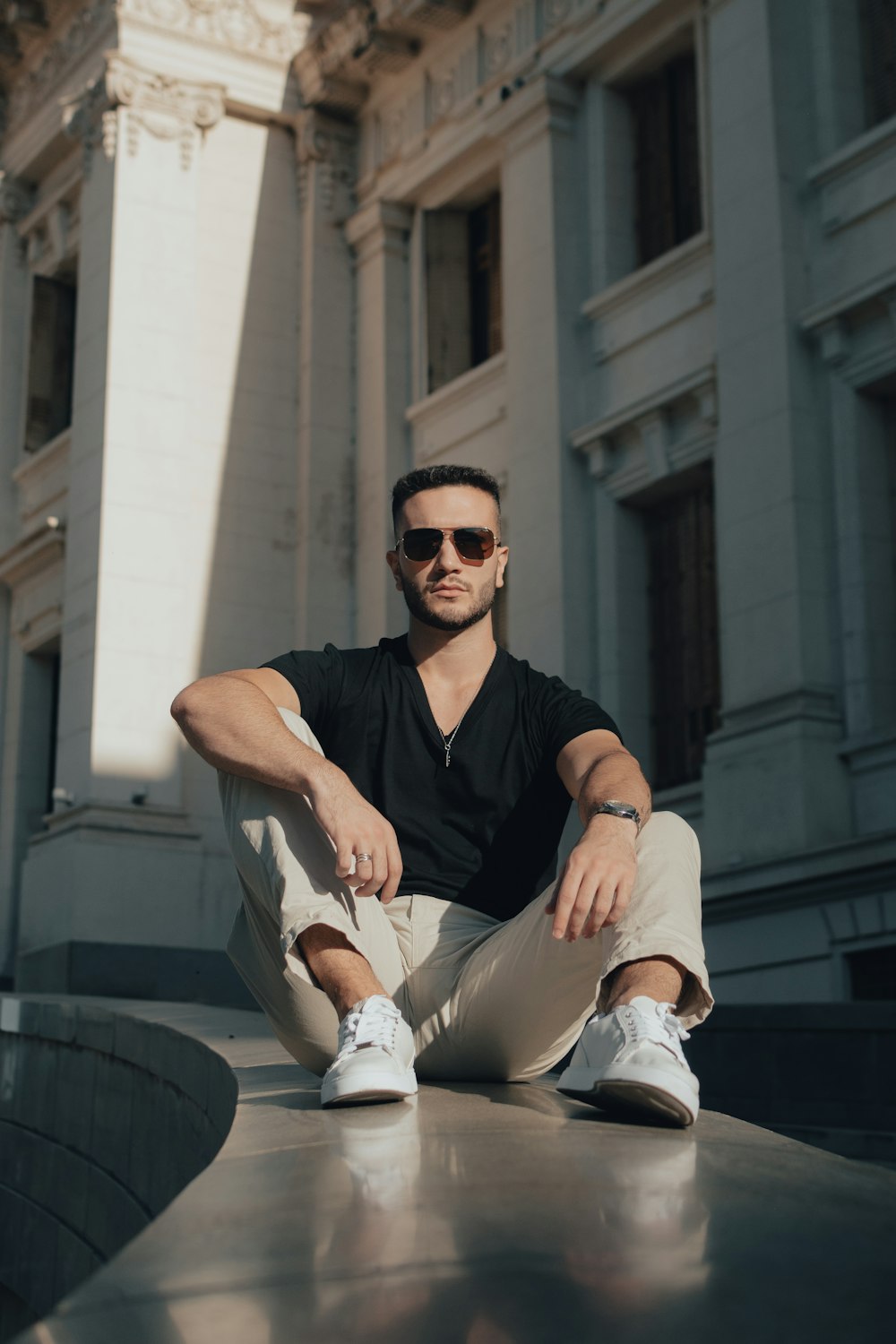 a man sitting on the ground in front of a building