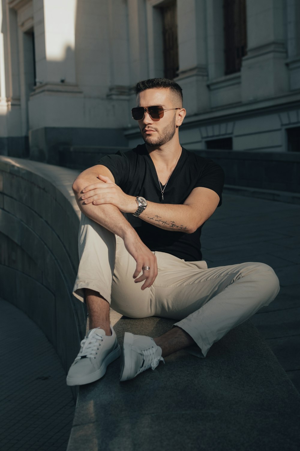 a man sitting on a ledge with his arms crossed