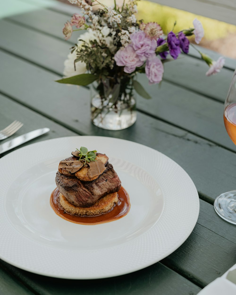 a white plate topped with food next to a glass of wine