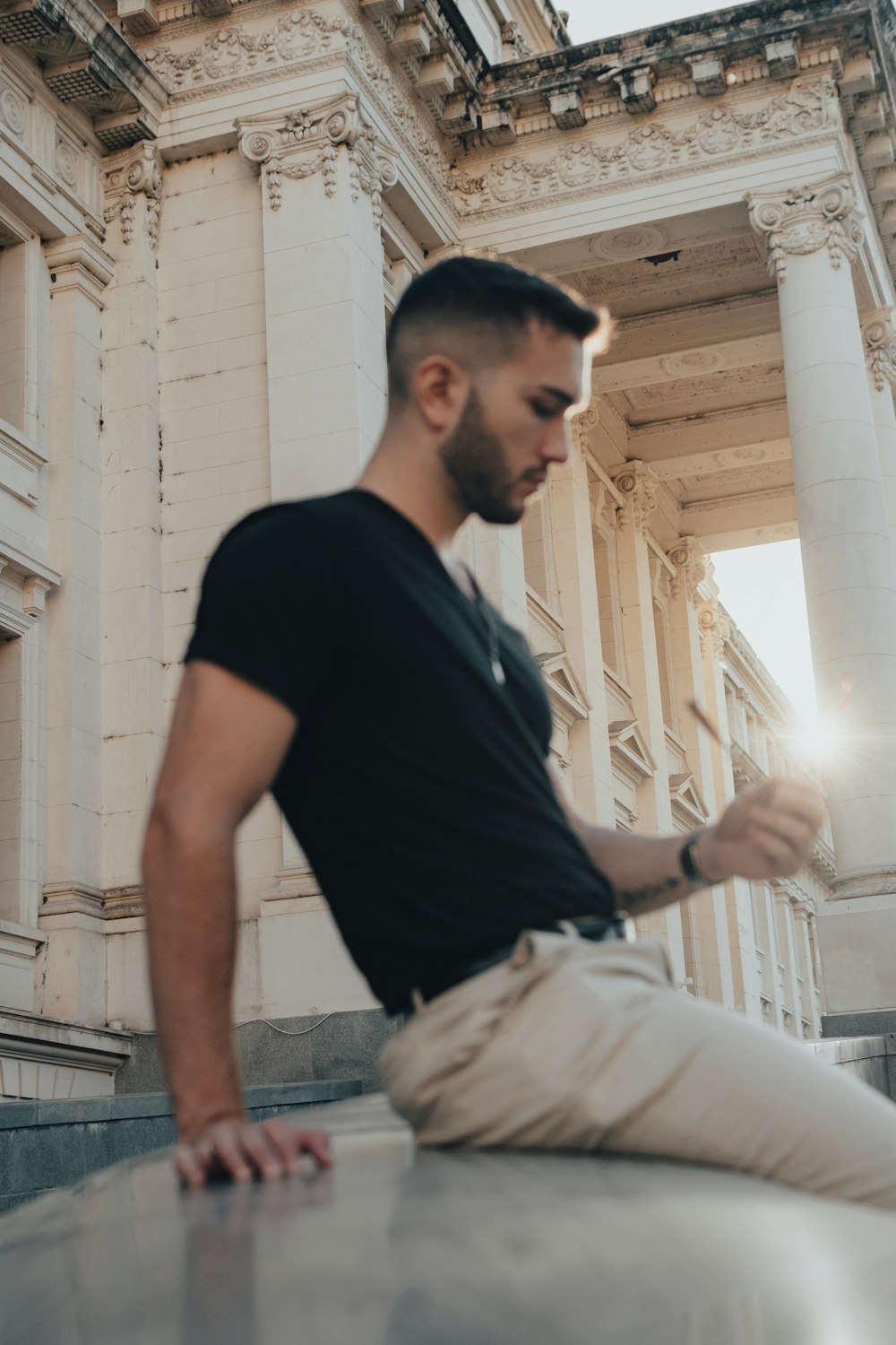 a man sitting on a ledge in front of a building