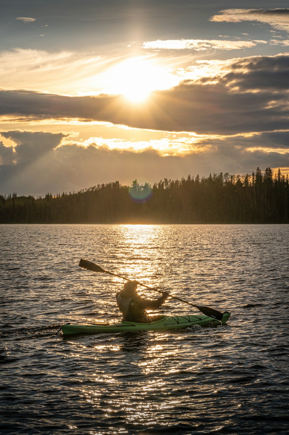 a person on a kayak in the water at sunset