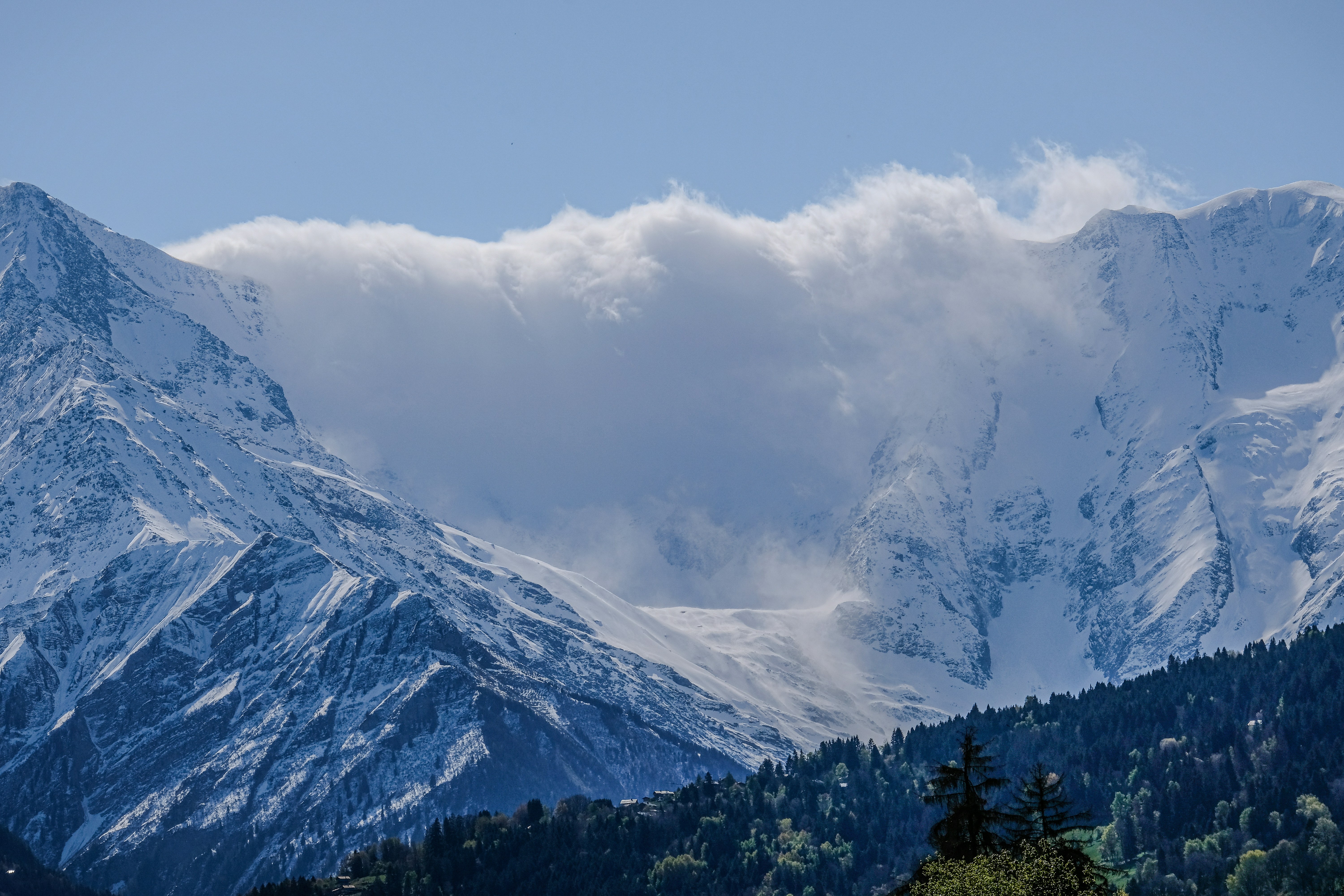 a mountain range covered in snow under a cloudy sky