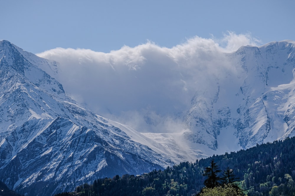 a mountain range covered in snow under a cloudy sky