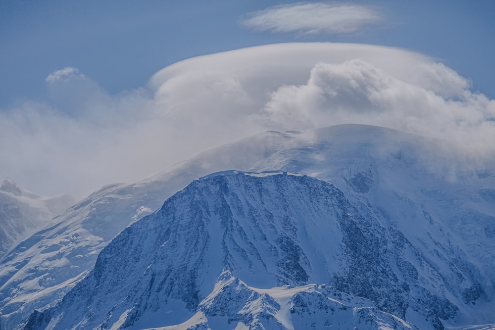 a snow covered mountain under a cloudy blue sky