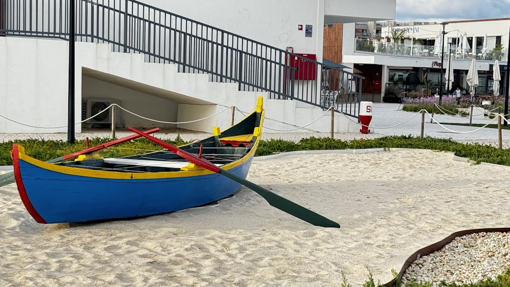 a blue and yellow boat sitting on top of a sandy ground