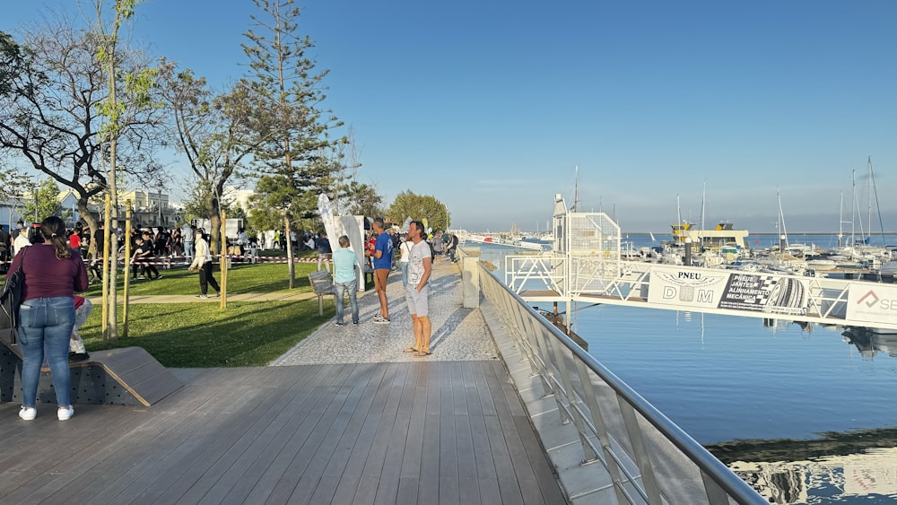 a group of people walking on a boardwalk next to a body of water