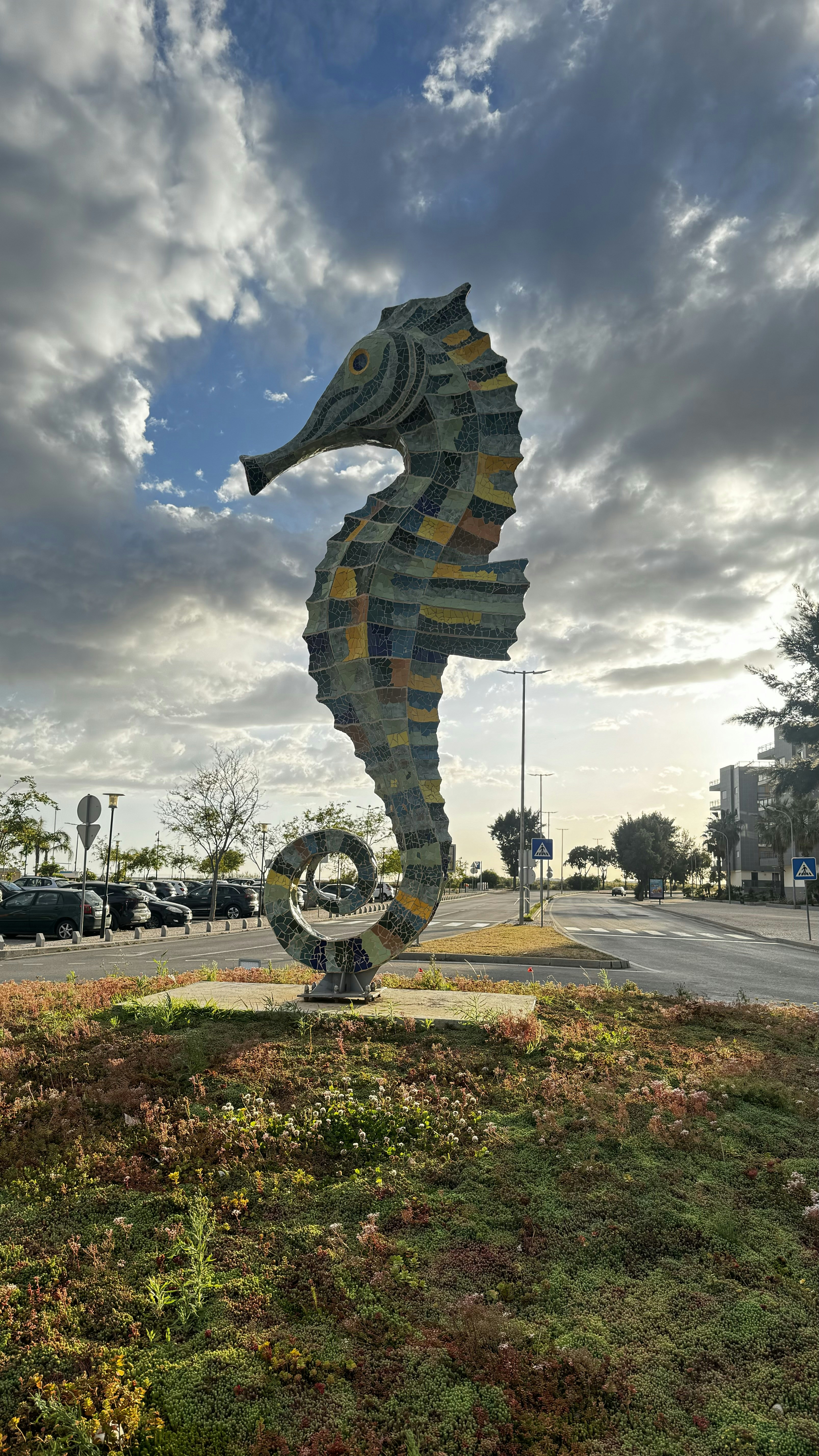 a large sea horse sculpture sitting on top of a lush green field