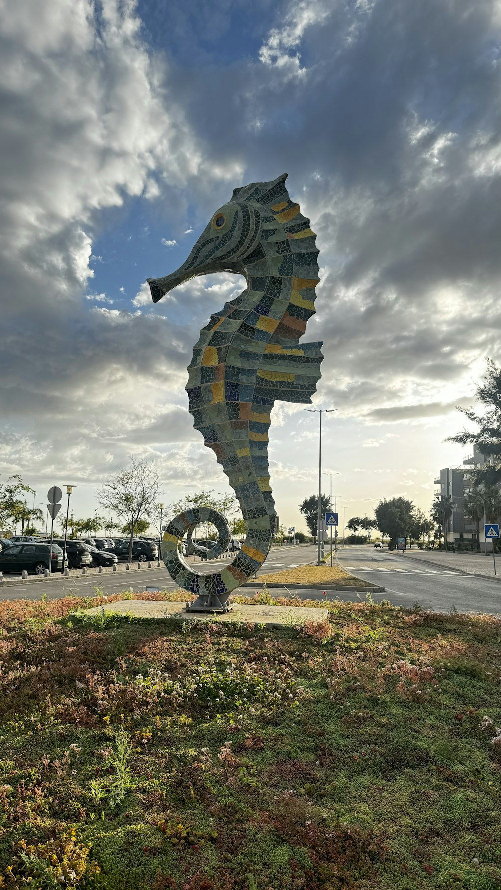 a large sea horse sculpture sitting on top of a lush green field