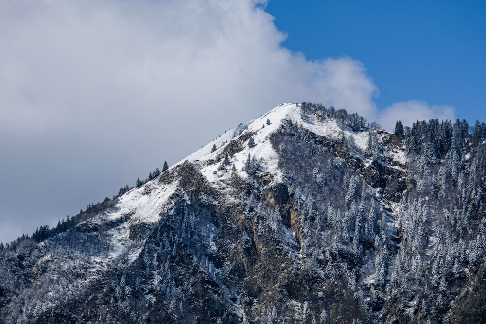 a mountain covered in snow under a cloudy blue sky