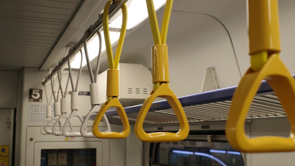 a row of yellow handles hanging from the ceiling of a train