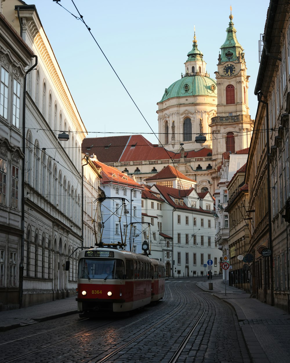 a red trolley car traveling down a street next to tall buildings