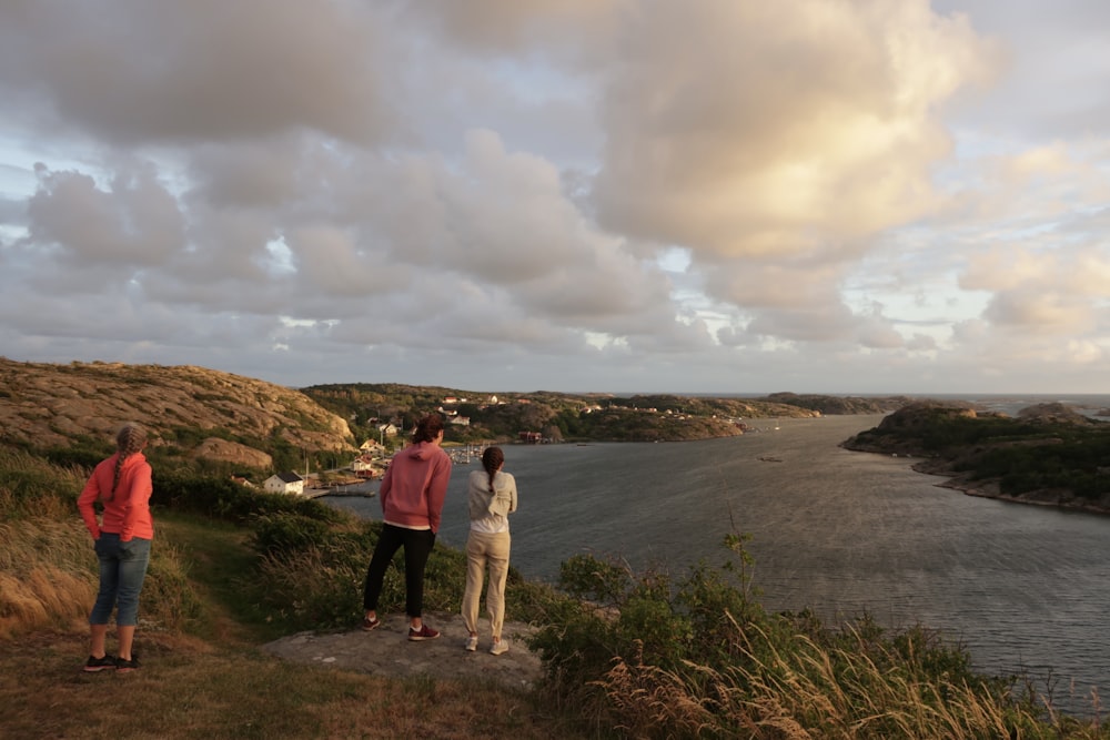 a group of people standing on top of a lush green hillside