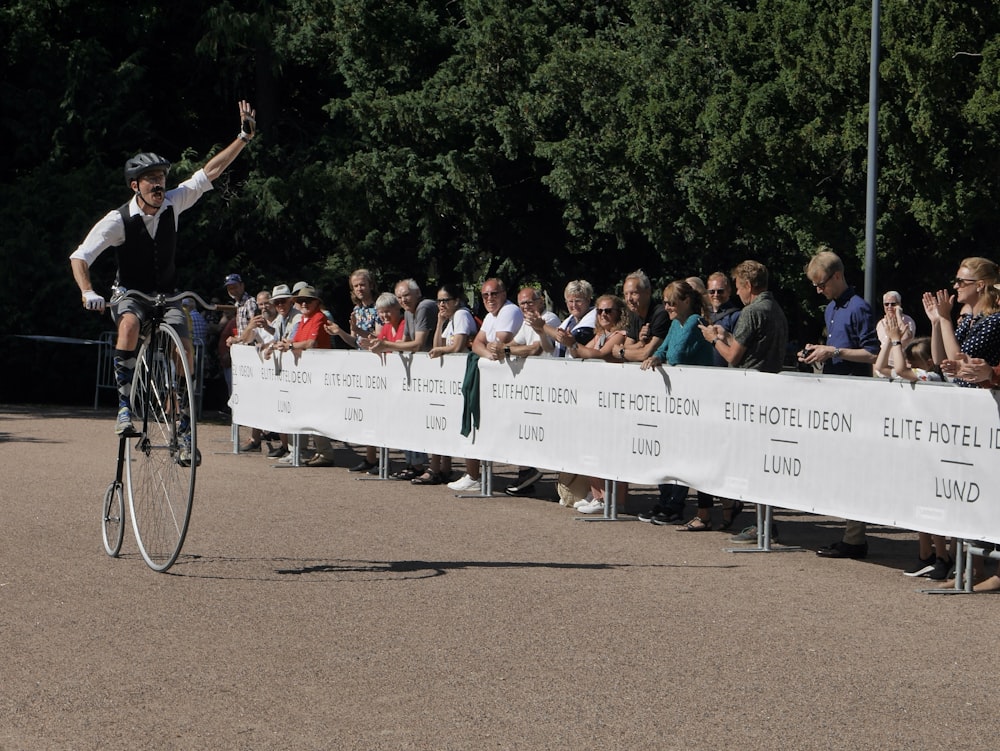 a man riding a bike past a crowd of people