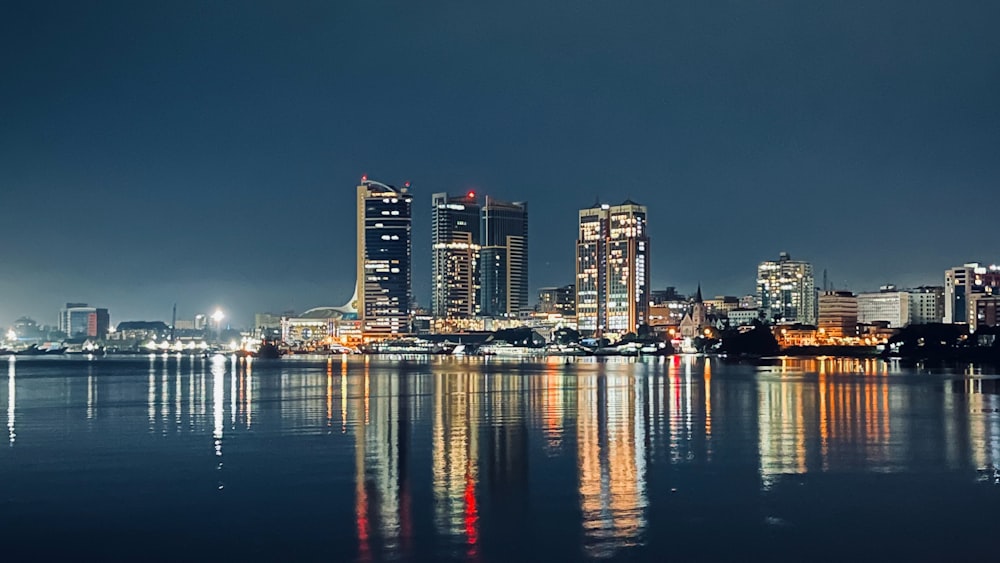 a city skyline is reflected in the water at night