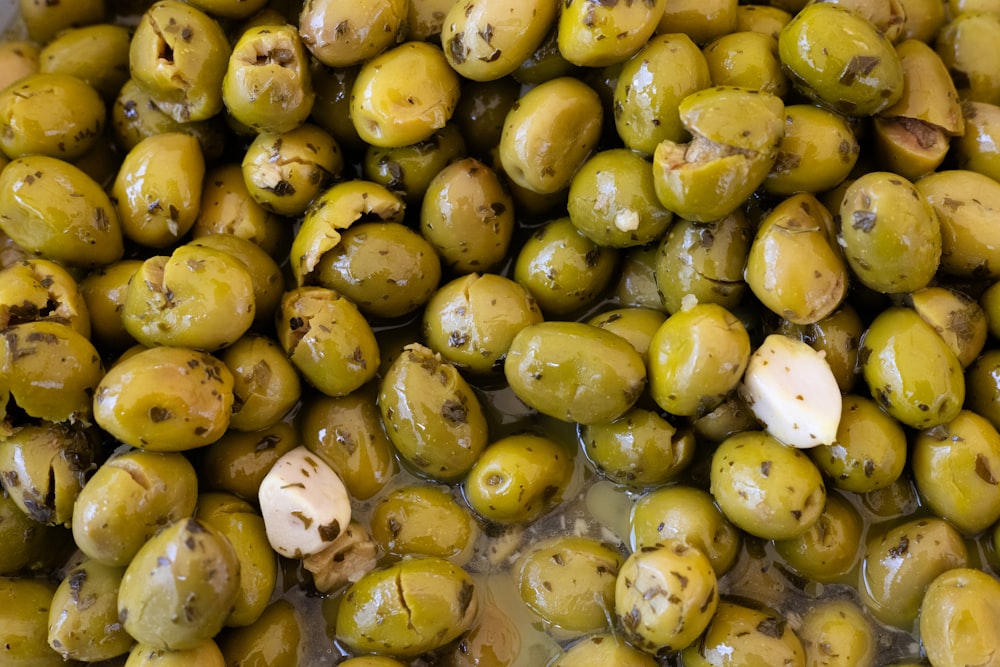 a pile of green olives with brown spots on them