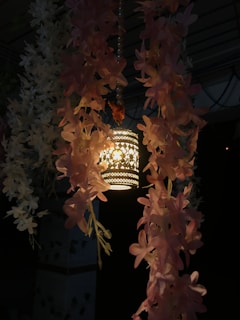 a light hanging from a ceiling next to a bunch of flowers