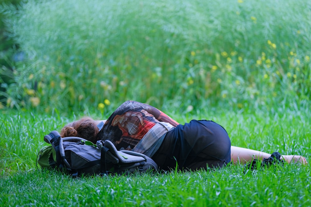 a person laying in the grass with a backpack