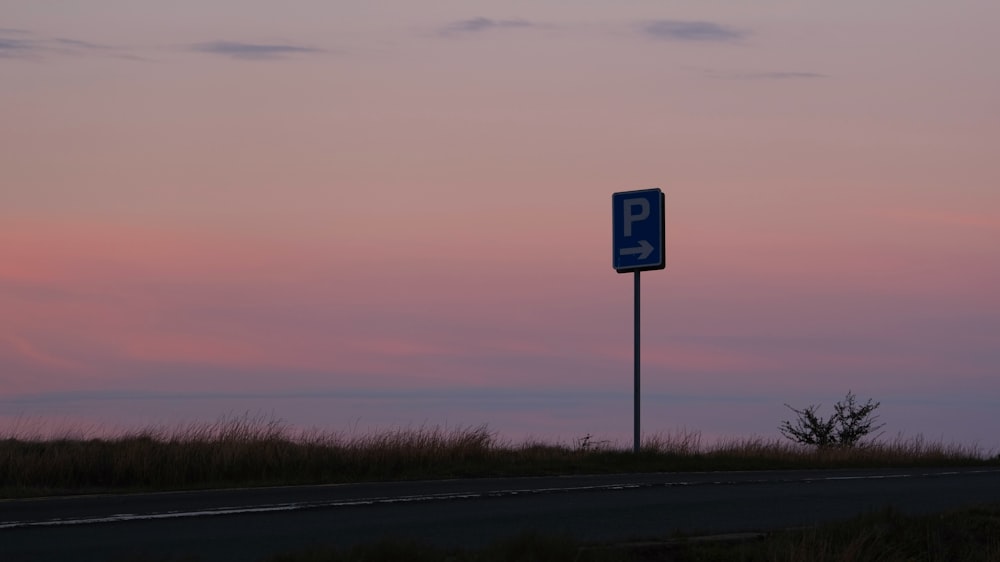 a blue parking sign sitting on the side of a road