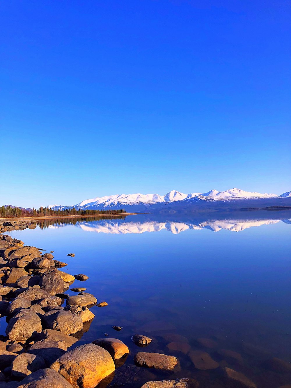 a body of water surrounded by rocks and snow capped mountains