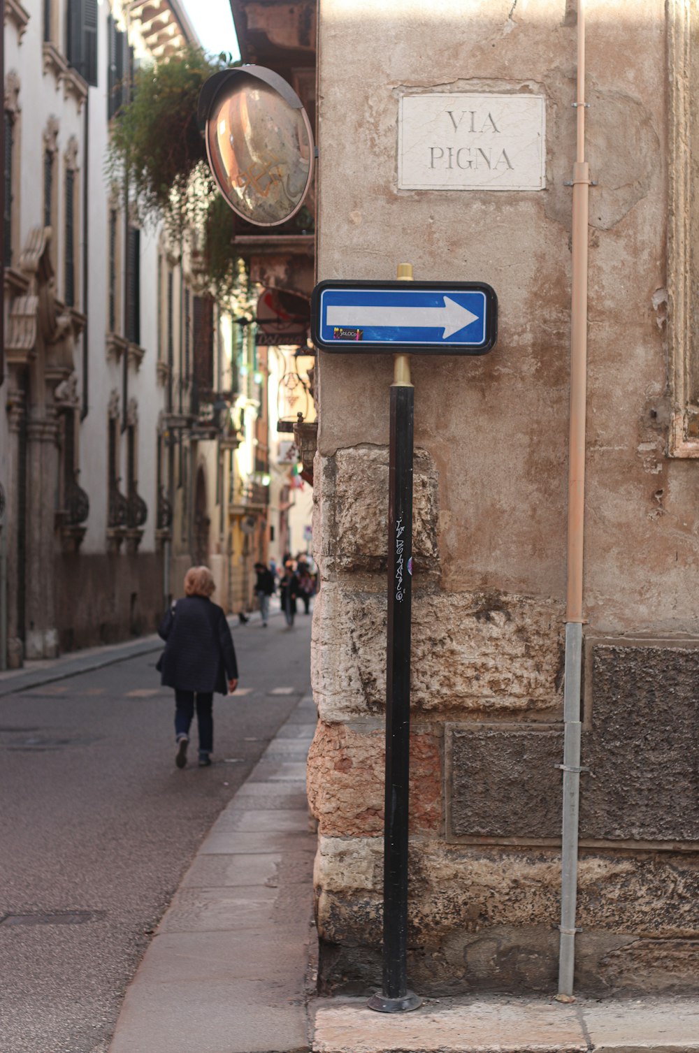 a woman walking down a street next to a tall building