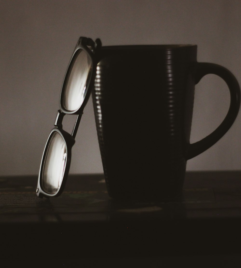 a pair of glasses sitting on top of a black cup