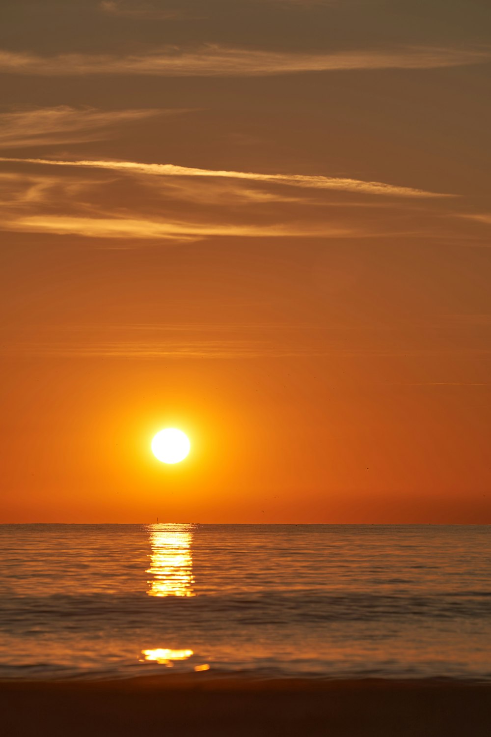 the sun is setting over the ocean on a beach