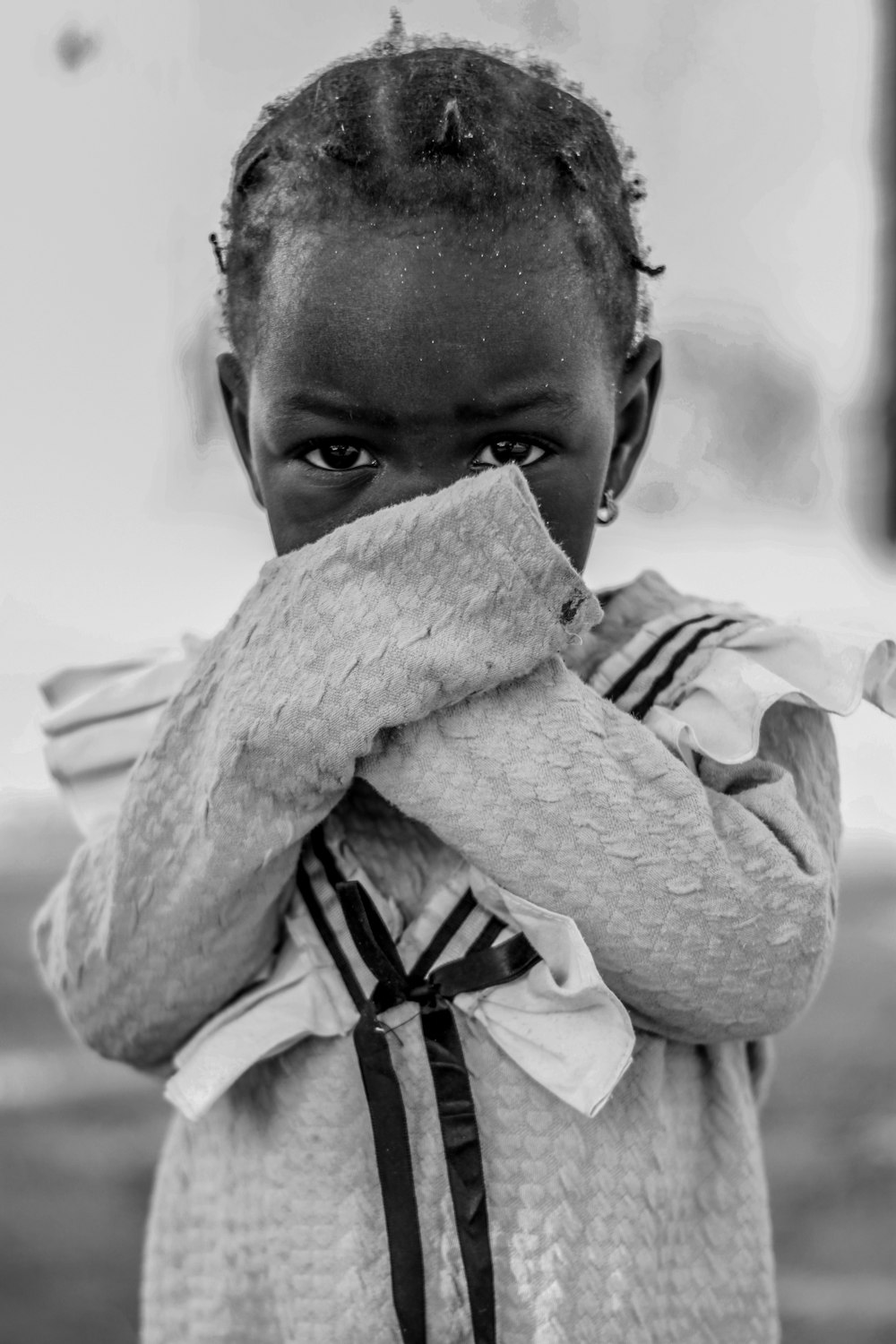 a black and white photo of a young girl covering her face