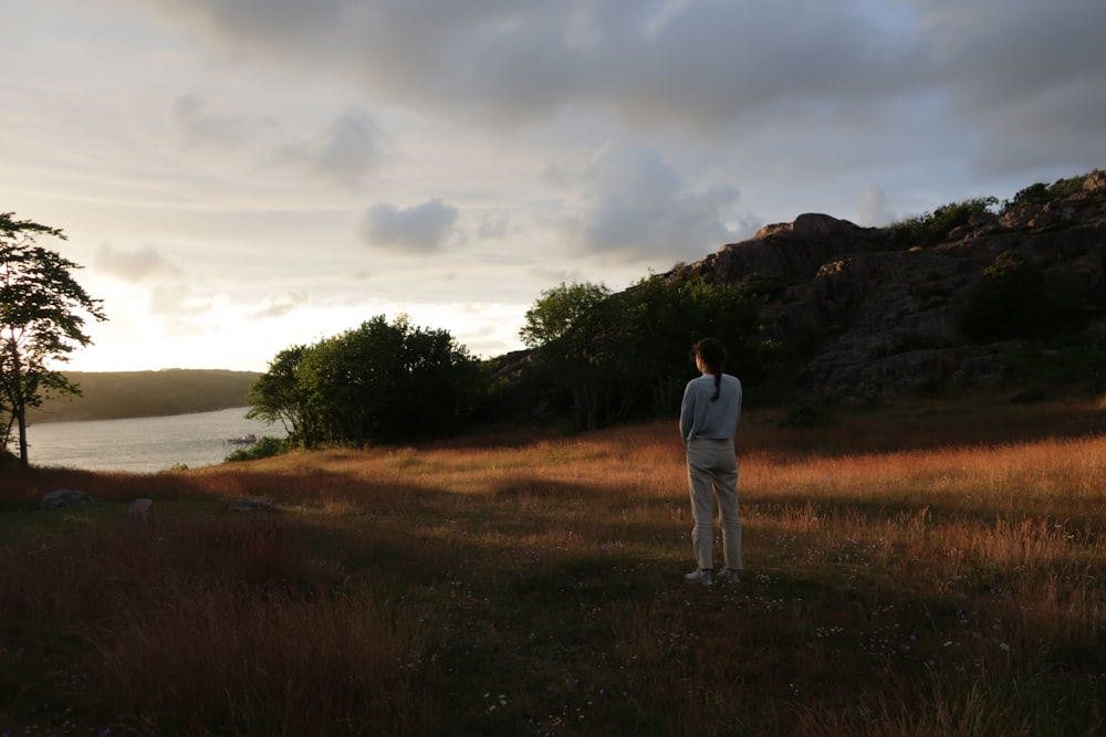 a man standing in a field next to a body of water