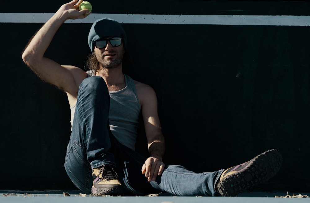 a man sitting on the ground with a tennis ball in his hand