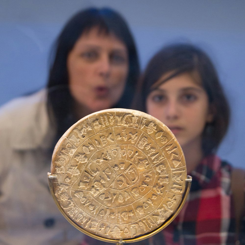 a woman and a girl looking at a gold coin