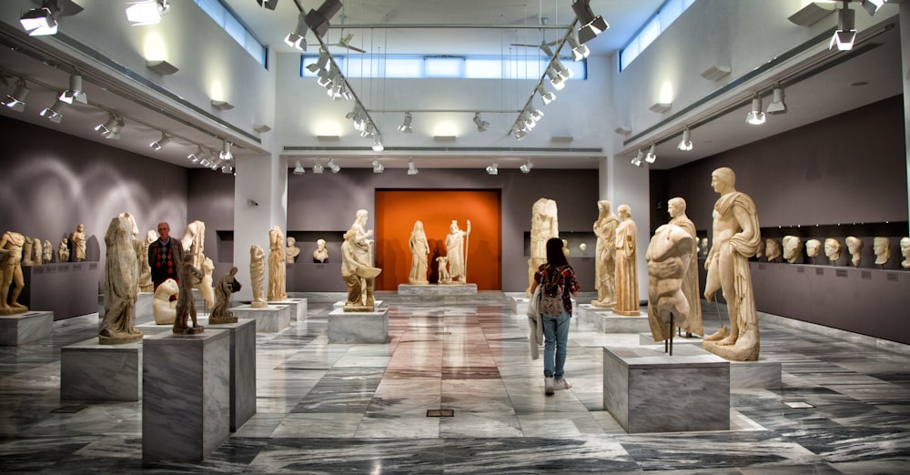 a woman standing in front of a bunch of statues